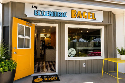 The Eccentric Bagel storefront on Shelter Island, with its yellow door open and an open sign in the window